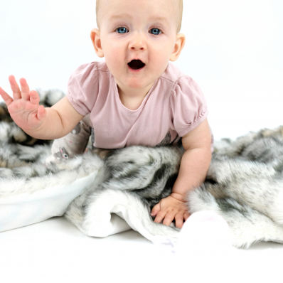 photo shoot of a cute baby with big blue eyes crawling on a fur rug