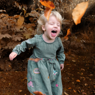 Young girl playing in the autumn leaves