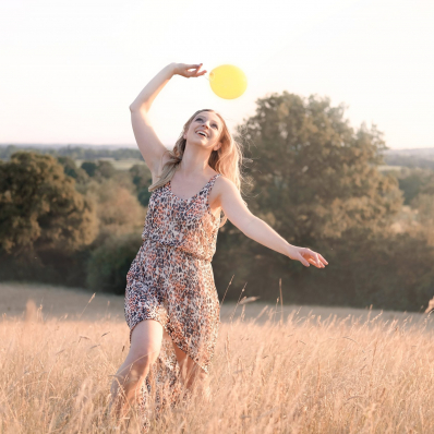 girl playing with a yellow balloon in a sunset field in redditch worcestershire